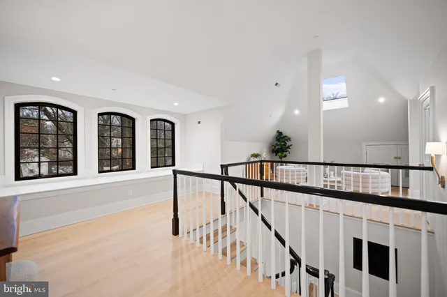a view of staircase and white kitchen with wooden floor