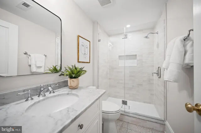 a bathroom with a granite countertop sink a toilet and shower