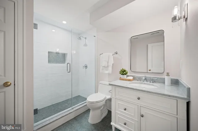a bathroom with a granite countertop sink toilet a large mirror a shower and vanity