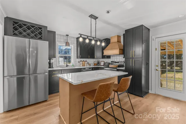 a kitchen with stainless steel appliances granite countertop a refrigerator a sink a stove and a wooden floors