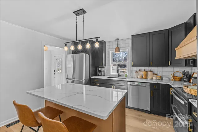 a kitchen with stainless steel appliances kitchen island granite countertop a sink a stove a refrigerator a dining table and chairs