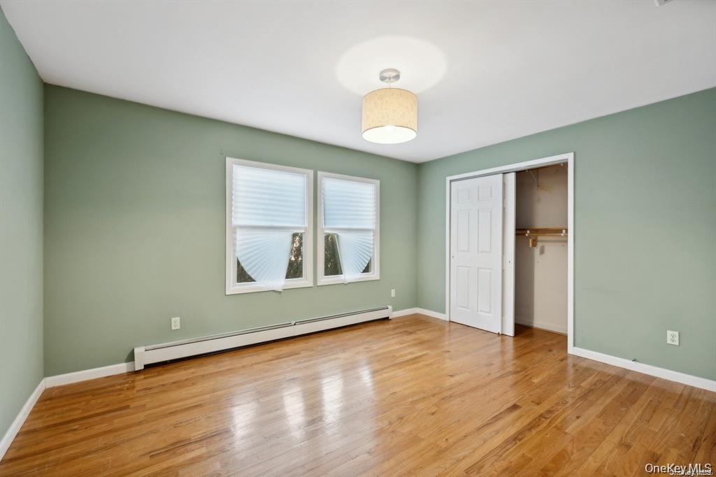 301 Laurel Road Northport, NY 11768 - Photo 11 of 12 Unfurnished bedroom with baseboard heating, light wood finished floors, and a closet