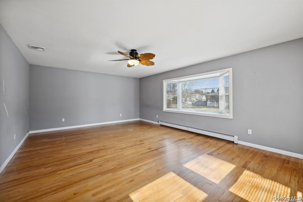 301 Laurel Road Northport, NY 11768 - Photo 12 of 12 Empty room featuring a baseboard heating unit, light wood finished floors, and ceiling fan