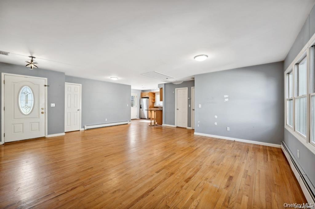 301 Laurel Road Northport, NY 11768 - Photo 10 of 12 Unfurnished living room featuring baseboard heating, light wood-style floors, and a baseboard heating unit