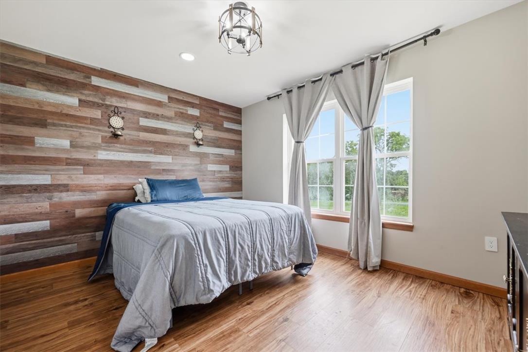387 Blue Ridge Road Saylorsburg, PA 18353 - Photo 64 of 90 Natural light floods this inviting bedroom, featuring warm wood flooring and a distinctive accent wall.