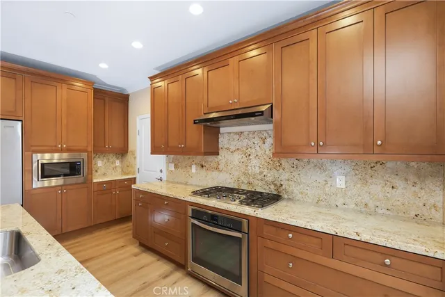 a kitchen with granite countertop cabinets stainless steel appliances and wooden floor