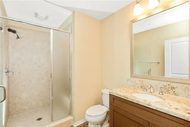 a bathroom with a granite countertop sink a toilet and shower