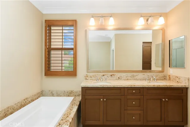 a bathroom with a sink vanity granite tub shower and a mirror
