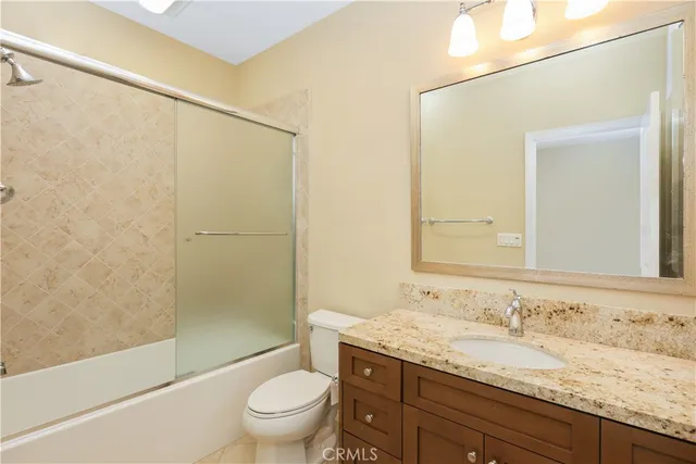 a bathroom with a granite countertop sink a toilet and shower