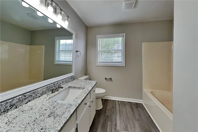 a bathroom with a granite countertop sink a toilet and window