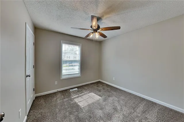 an empty room with a chandelier fan and windows