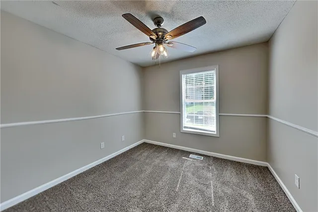 an empty room with a window and a ceiling fan