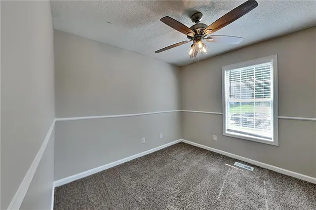 an empty room with a window and a ceiling fan