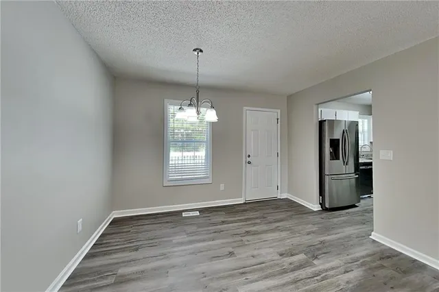 a view of empty room with wooden floor and kitchen