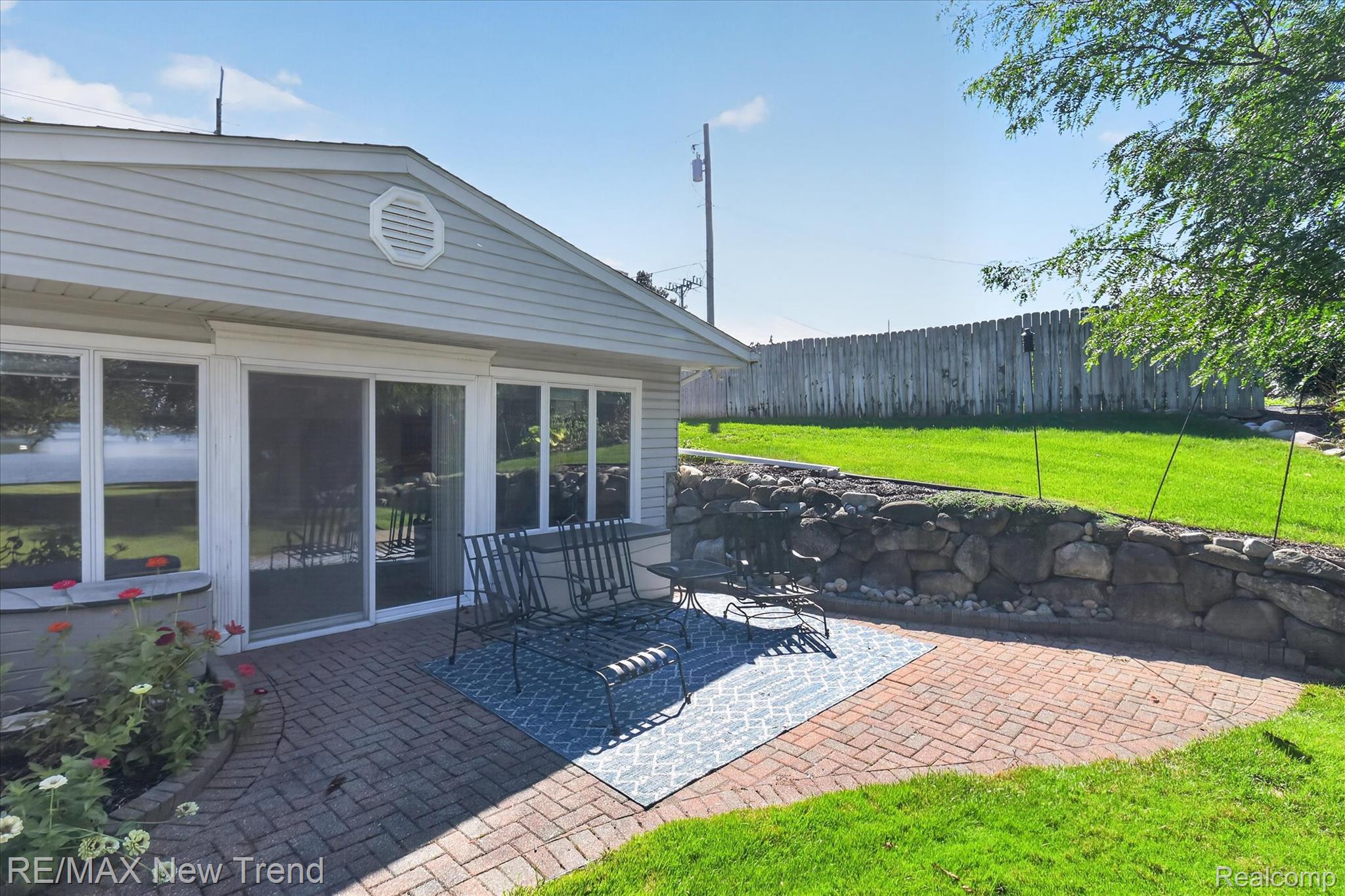 2529 South Commerce Road Walled Lake, MI 48390 - Photo 46 of 66 Brick paver patio with a stone retaining wall, sliding glass doors, and a manicured lawn