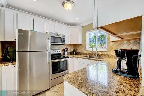 a kitchen with granite countertop a refrigerator stove top oven and sink