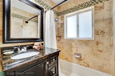 a bathroom with a granite countertop sink a mirror and a bathtub