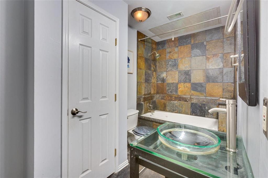 4104 North Hall Street, Unit 102 Dallas, TX 75219 - Photo 16 of 18 Bathroom featuring a glass vessel sink, chrome single-handle faucet, and glass vanity top