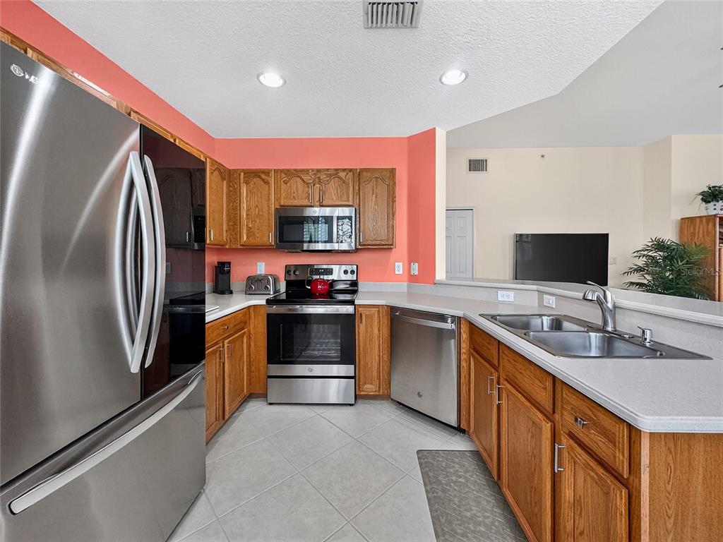 920 Spring Park Street, Unit 303 Celebration, FL 34747 - Photo 11 of 40 a kitchen with stainless steel appliances kitchen island granite countertop a refrigerator and a sink