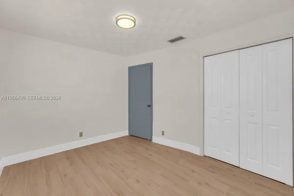 an empty room with wooden floor and closet