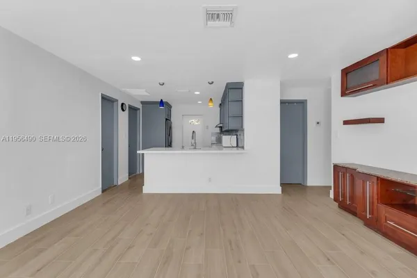 a view of a kitchen with kitchen island a sink wooden floor and a refrigerator