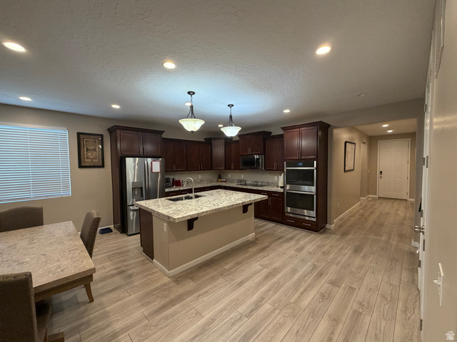 118 Tram Rock Rd. Lake Point, UT 84074 - Photo 9 of 34 Open-concept kitchen featuring wood-finish flooring, dark wood cabinetry, stainless steel appliances, a center island with a granite-style countertop, and recessed lighting