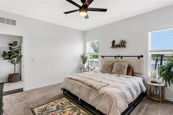 a bedroom with a bed and a potted plant on the dresser