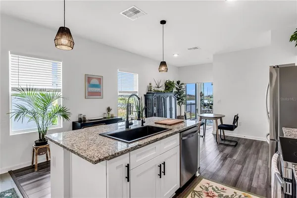 a kitchen with stainless steel appliances granite countertop a sink a counter space and wooden floor