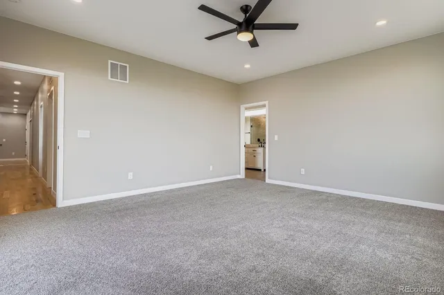 an empty room with a ceiling fan and carpet