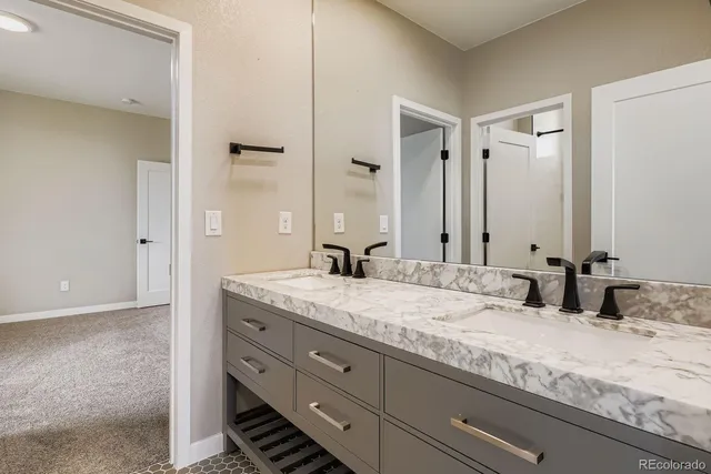 a bathroom with a granite countertop double vanity sink and mirror