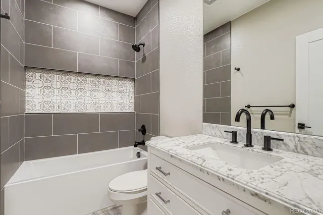 a bathroom with a granite countertop bathtub sink vanity mirror and toilet