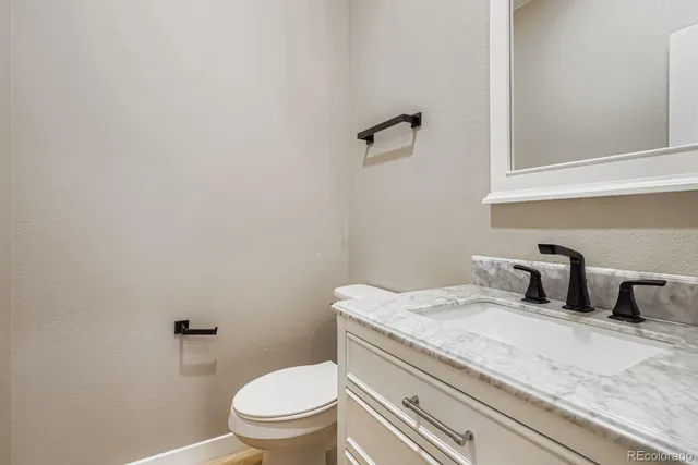 a bathroom with a granite countertop toilet and a sink
