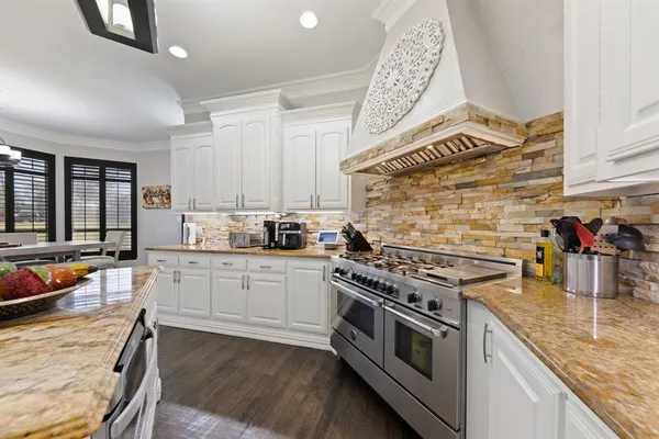 a kitchen with stainless steel appliances granite countertop a stove a sink dishwasher and cabinets with wooden floor