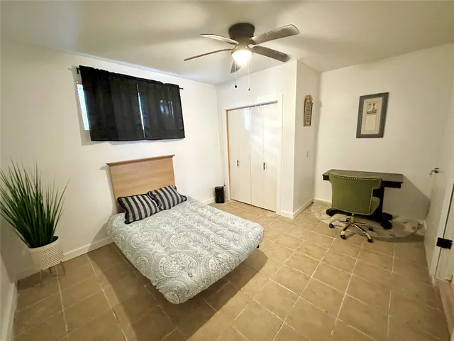 a bedroom with a bed a mirror and a potted plant