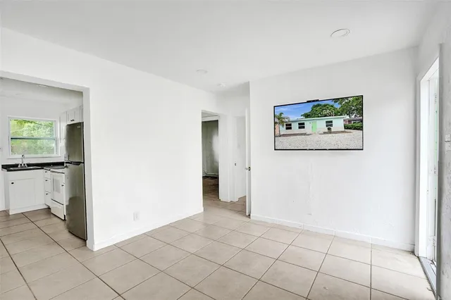 a view of livingroom with refrigerator and white cabinets