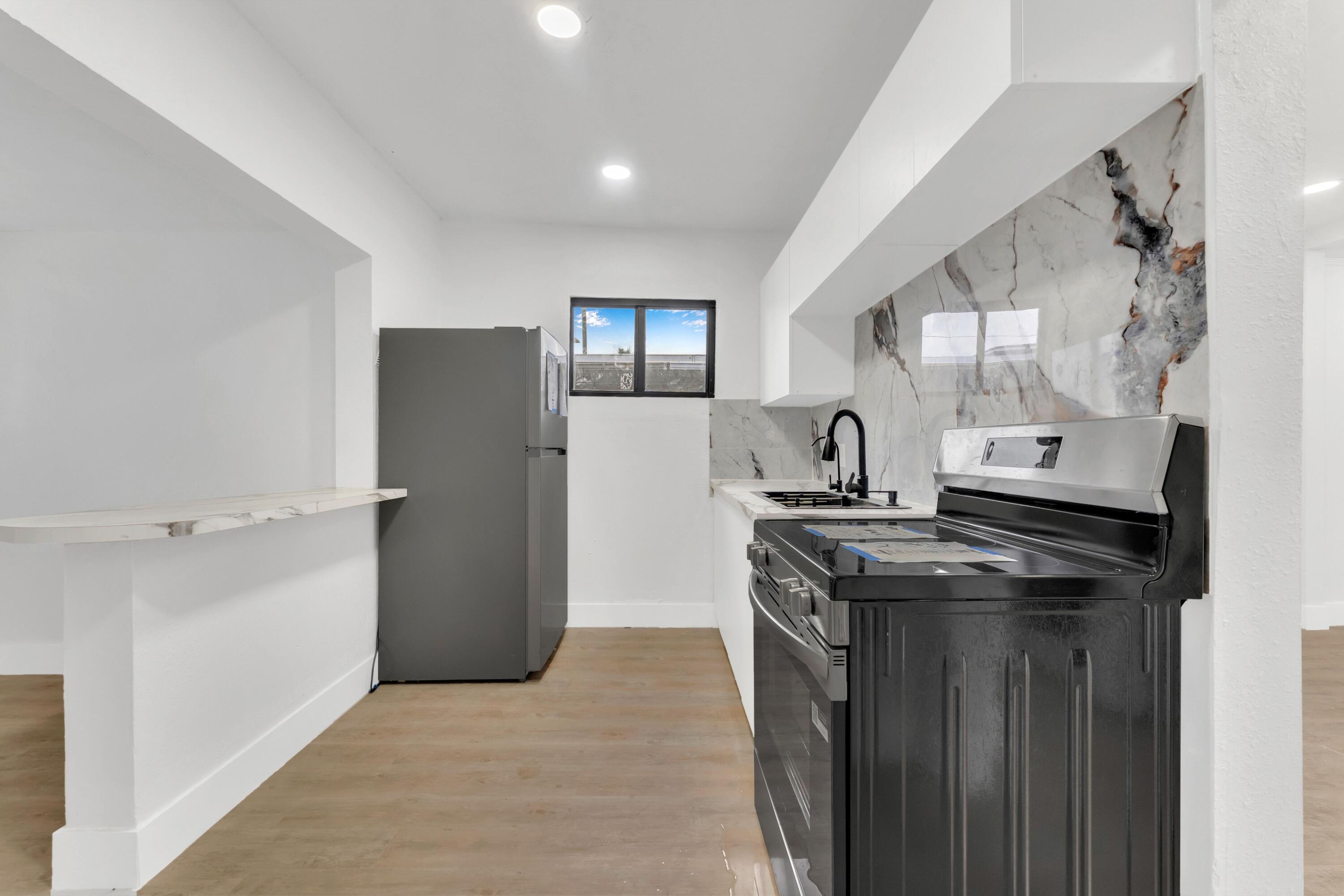 2428 Northwest 28th Street Miami, FL 33142 - Photo 8 of 19 a kitchen with stainless steel appliances granite countertop a refrigerator and a sink