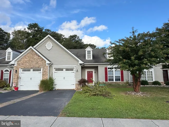 a view of white house with a big yard plants and large trees
