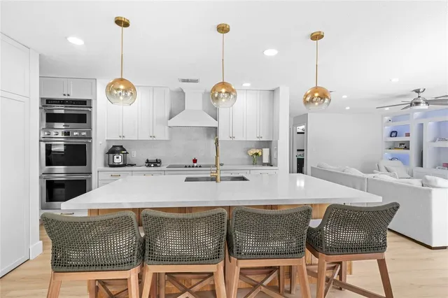 a kitchen with stainless steel appliances kitchen island granite countertop a table chairs and a wooden floor