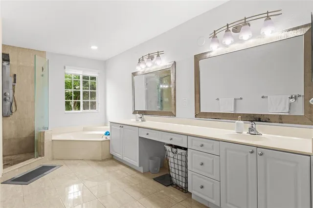 a spacious bathroom with a double vanity sink large mirror and a bathtub