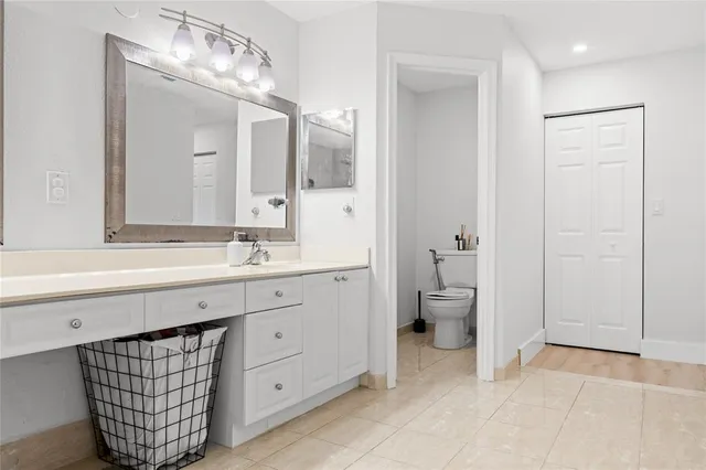 a spacious bathroom with a double vanity sink a toilet and a mirror