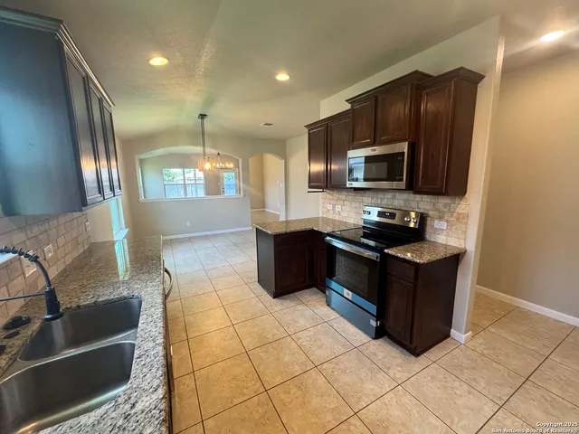 a kitchen with stainless steel appliances granite countertop a stove a sink and a microwave