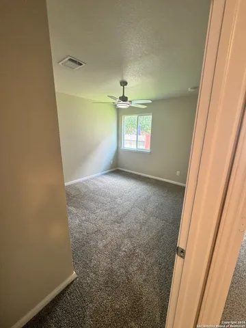 an empty room with a ceiling fan and window