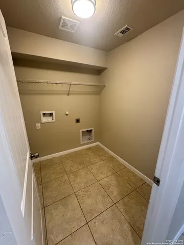 an empty room with a chandelier fan and windows