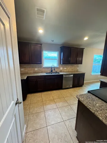 a large kitchen with kitchen island granite countertop a sink and a stove top oven