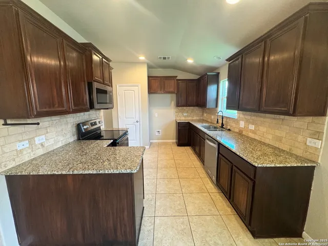 a kitchen with stainless steel appliances granite countertop wooden cabinets a granite counter top and a sink