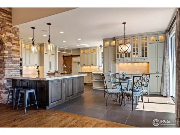 a open kitchen with stainless steel appliances granite countertop a table chairs sink and window