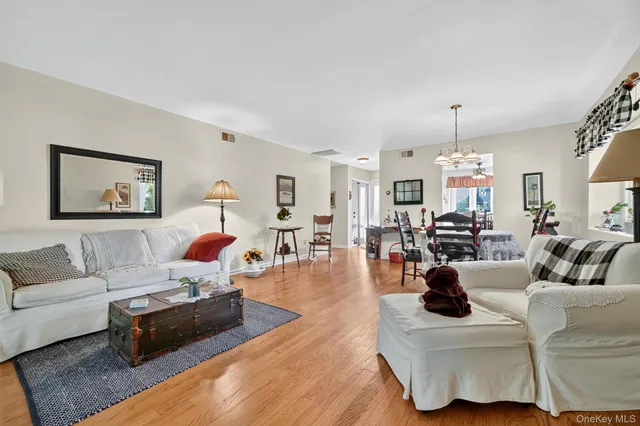 a living room with furniture kitchen view and a wooden floor