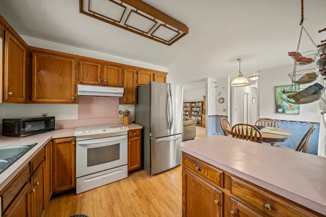 a kitchen with stainless steel appliances granite countertop a sink a stove a refrigerator cabinets and a dining table