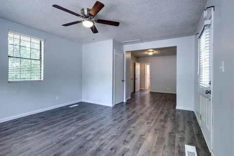 a view of an empty room with wooden floor and a window