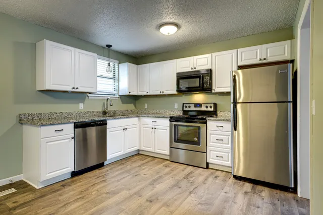 a kitchen with cabinets stainless steel appliances and a window